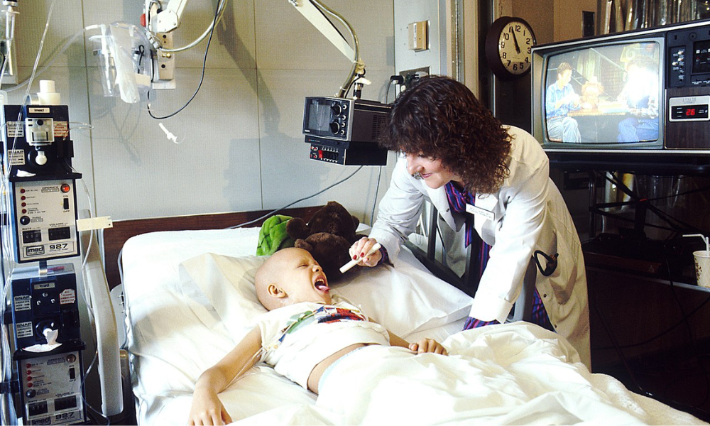 pediatra médica atendiendo niño en cama con cáncer