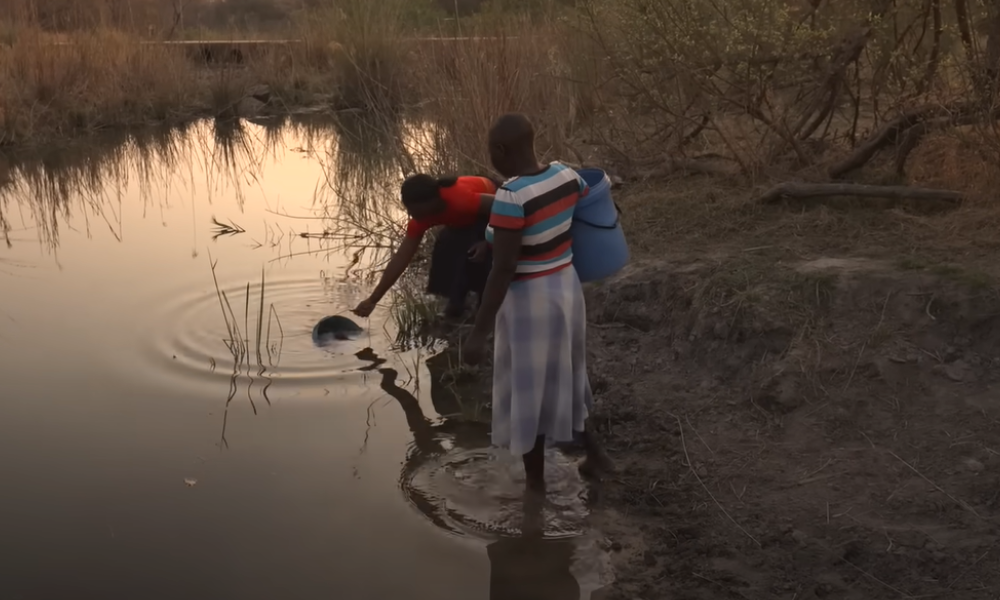 mujeres africanas de kenia recogiendo agua de un rio contaminado