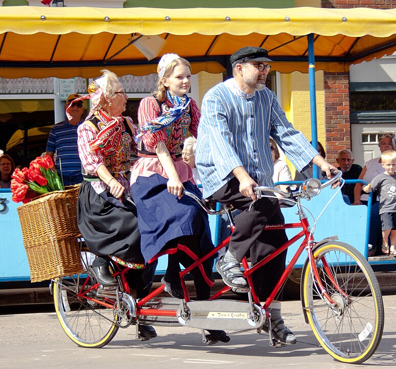 Tres personas viajando sobre una bicicleta tándem. 
