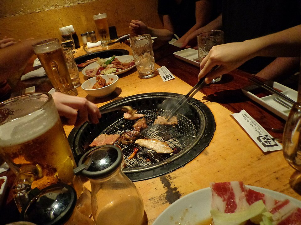 Un grupo de amigos prepara yakiniku en un bar.