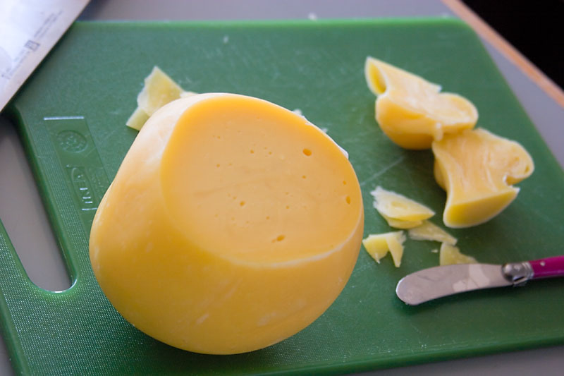 queso provolone amarillo sobre una tabla verde cortado