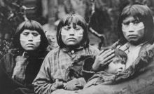 tres mujeres yaganes yamanas en blanco y negro con un bebé en brazos
