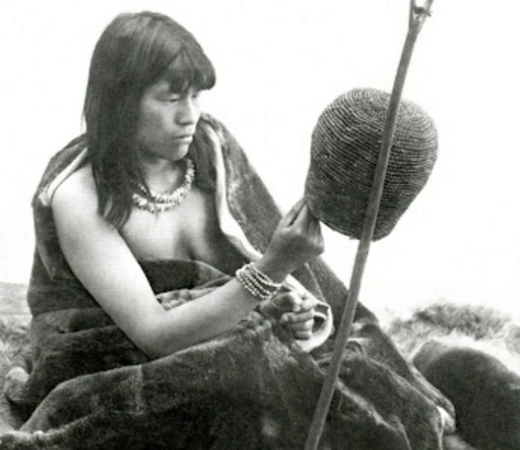 Mujer Yagán entre pieles de animales, utilizadas para protegerse de las bajas temperaturas. foto en blanco y negro.