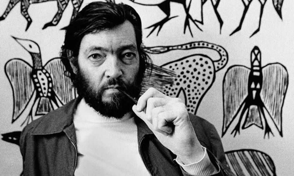 julio cortazar con fondo de dibujos y una lapicera en la boca