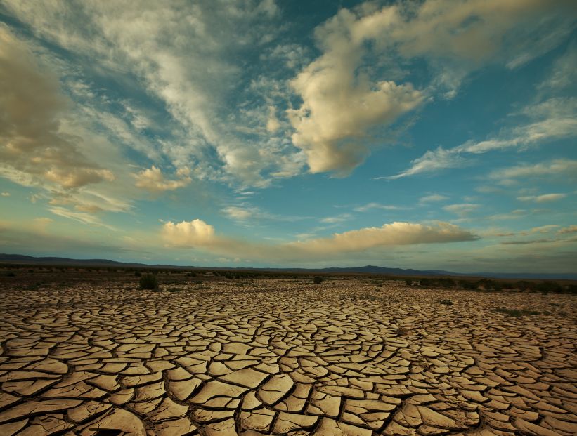 sequía. piso árido partido de un desierto con el cielo nublado y azul