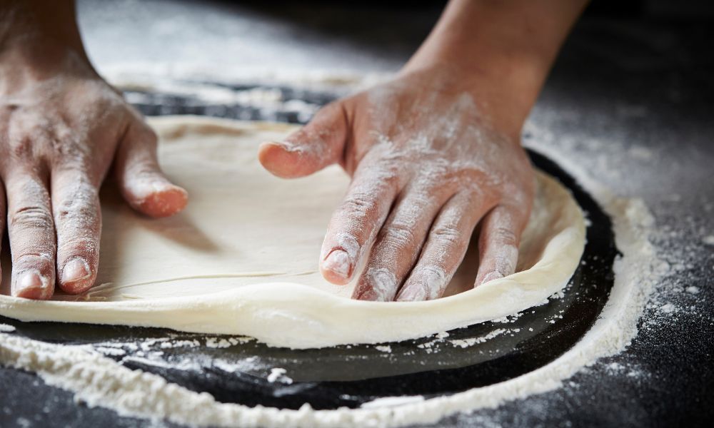 manos de pizzero haciendo la masa de una pizza