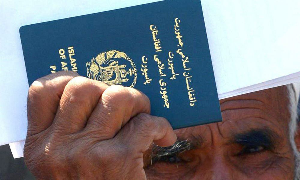 hombre afgano viejo con pelo blanco sosteniendo su pasaporte azul en la mano