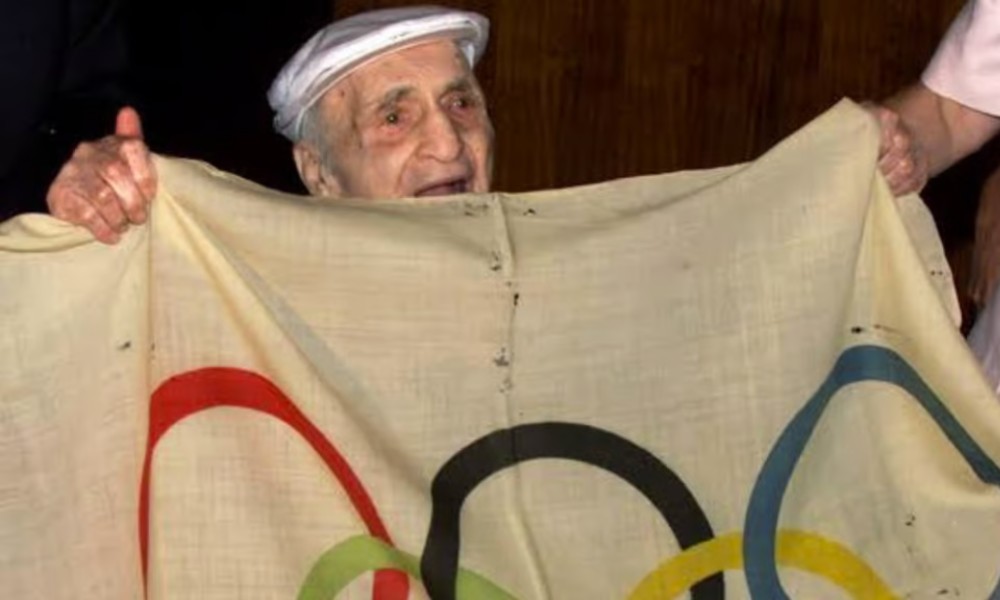 Harry Prieste, a los 103 años, con la bandera olímpica que robó en 1920