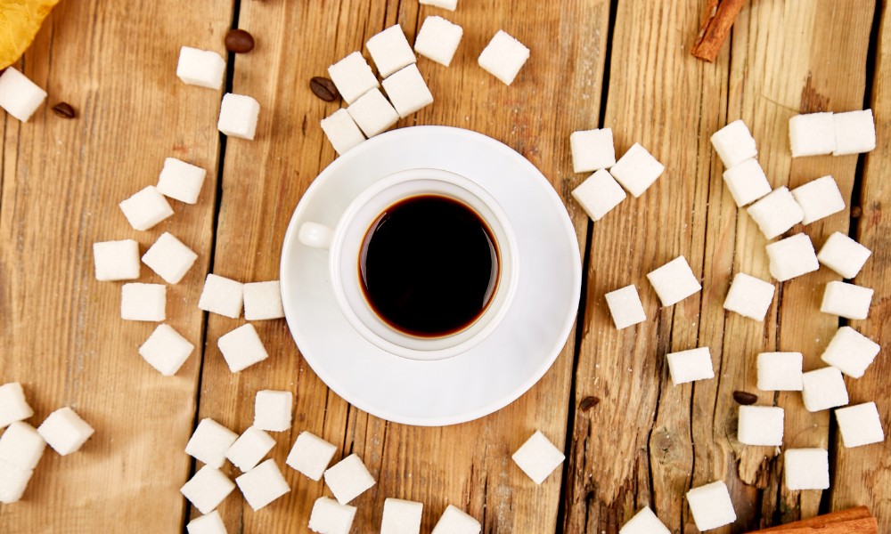 Taza de café junto a muchos terrones de azúcar