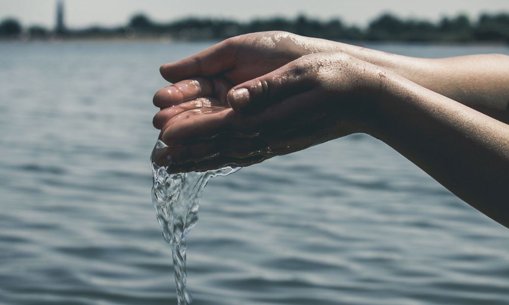 dos manos juntando agua y dejandola caer en el mar