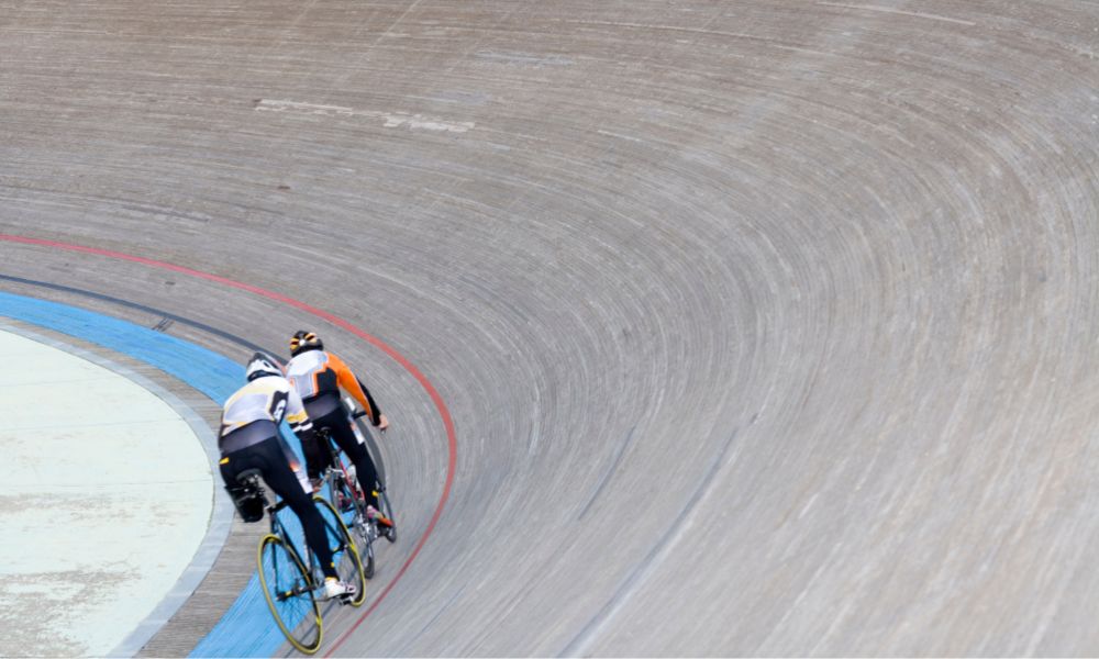 dos ciclistas en un velódromo gris