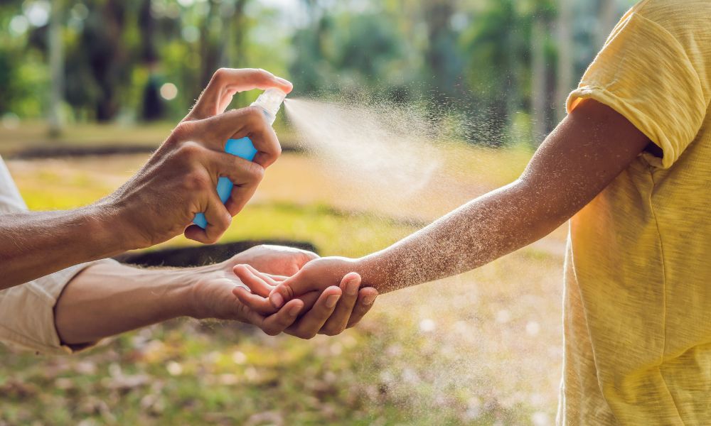 adulto poniendo repelente de mosquitos a un niño