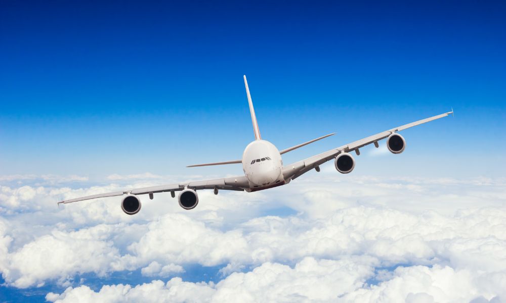 avión comercial blanco volando encima de las nubes visto de frente