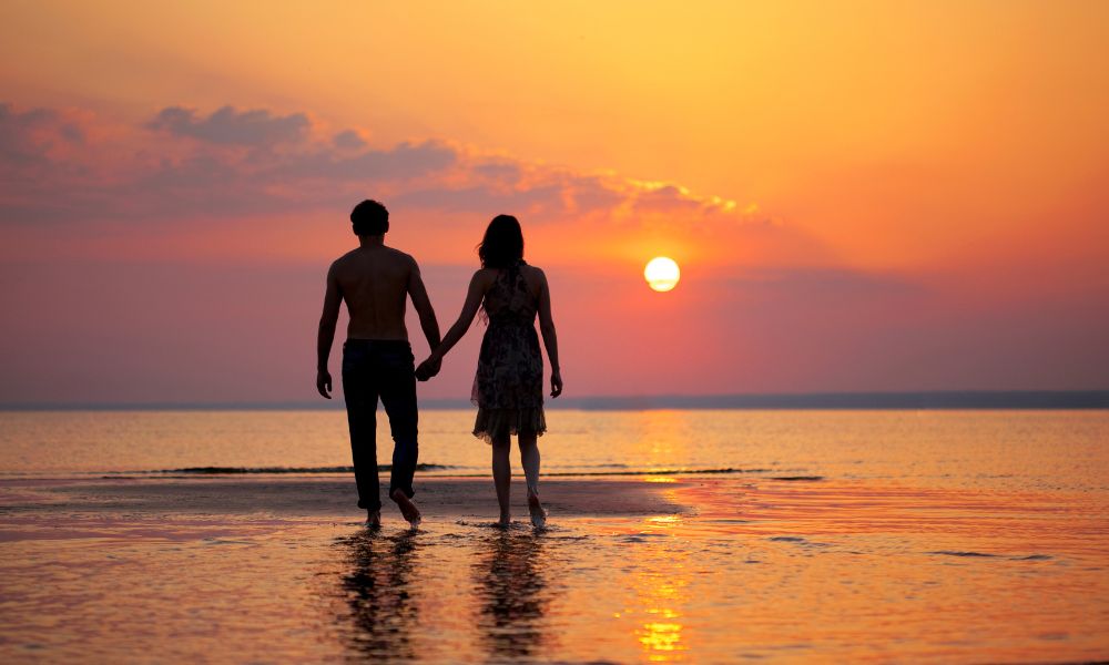 pareja enamorada caminando sobre el mar en el atardecer