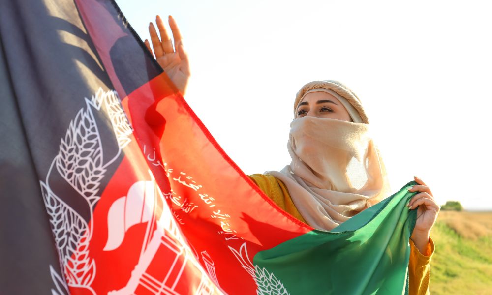 mujer afgana con velo puesto sosteniendo la bandera de afganistán