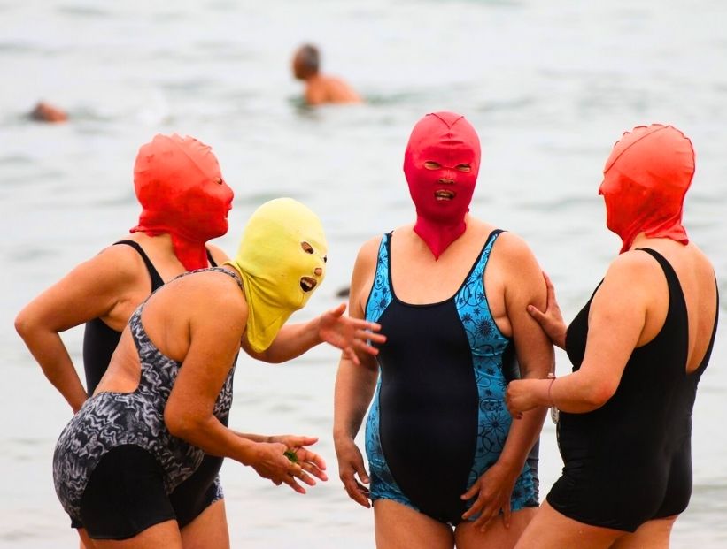 Mujeres chinas en el mar con facekini la cara cubierta