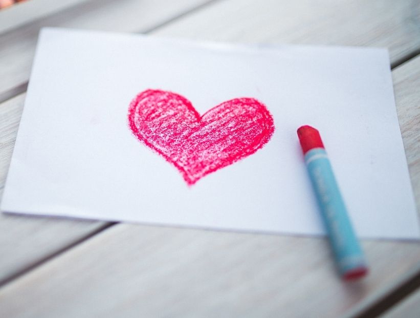 una hoja sobre la mesa y un corazón dibujado con crayón rosa