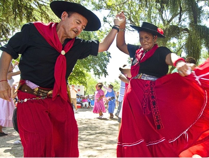 un señor y una señora bailan el chamamé vestidos con ropa tradicional del baile