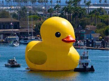 pato de goma gigante en un lago junto a barcos