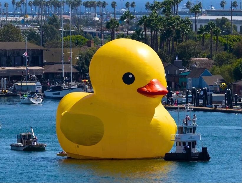 pato de goma gigante en un lago junto a barcos