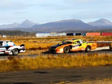 autódromo más al sur del mundo tres autos de carreras en un circuito con pastizales amarillos y marrones y montañas de fondo