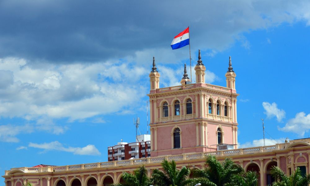 edificio histórico rosa en paraguay con la bandera nacional