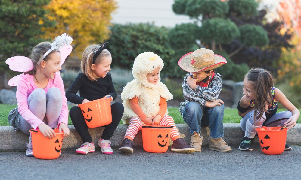 cinco niños disfrazados para halloween haciendo dulce o truco