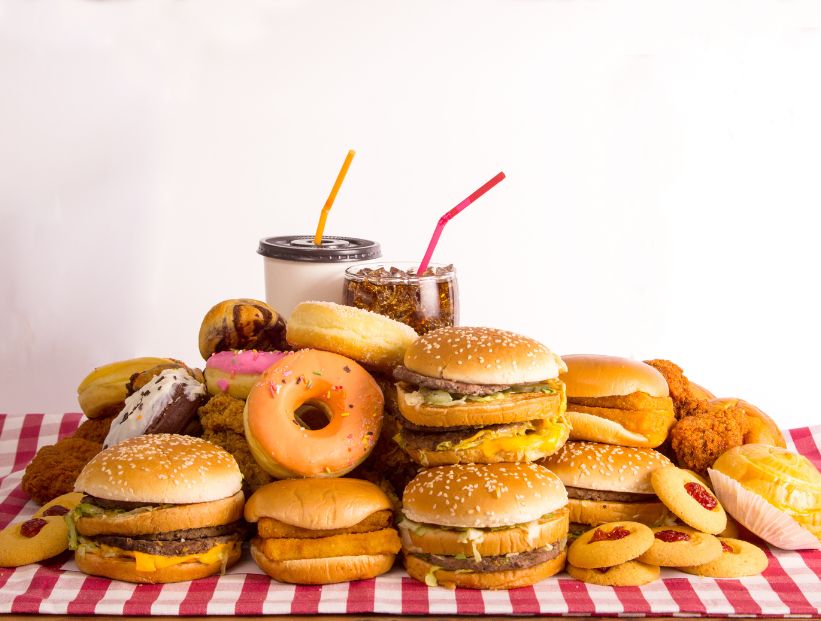 comida rápida hamburguesas donas y bebidas en una mesa