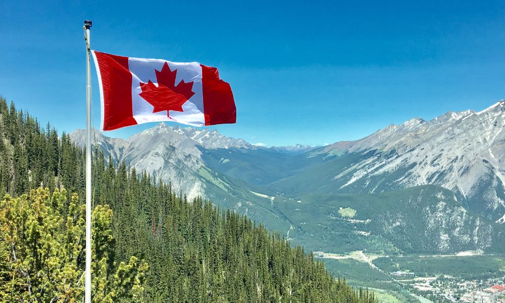 bandera de canadá flameando en las montañas